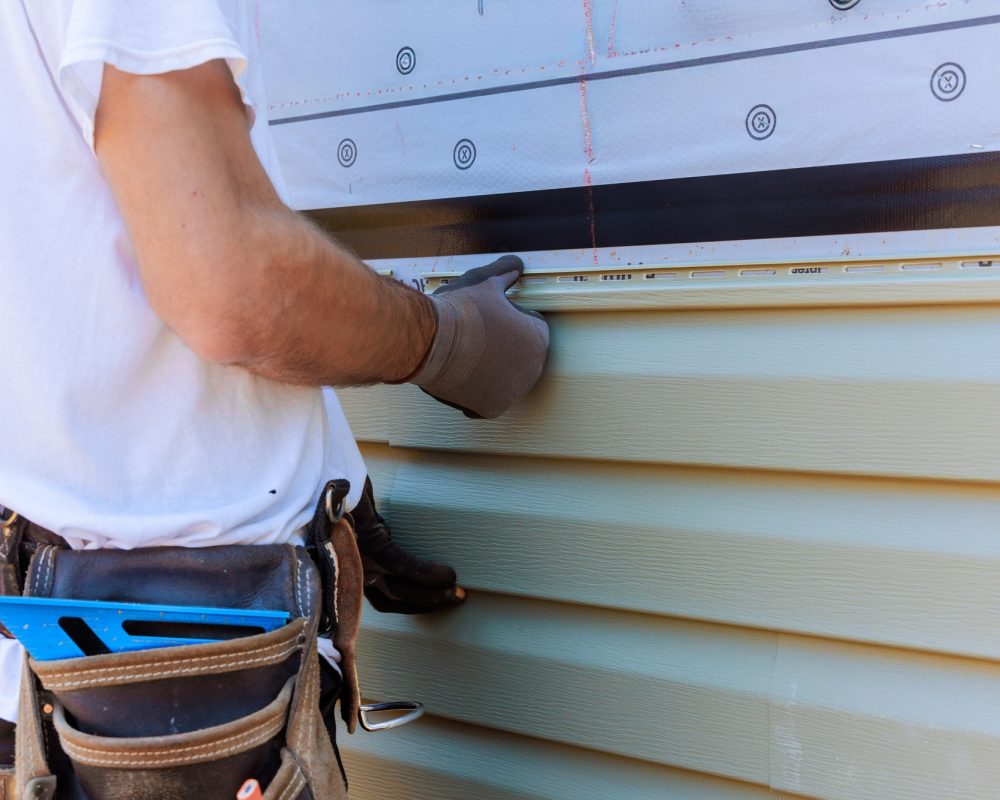 Handyman process installing vinyl PVC siding during construction on a facade new home