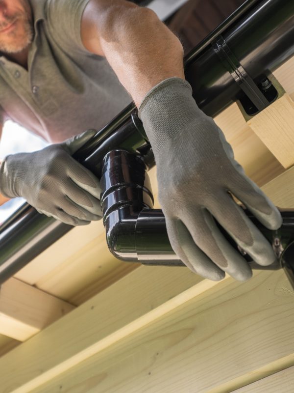 Worker Installing Gutter System on Roof
